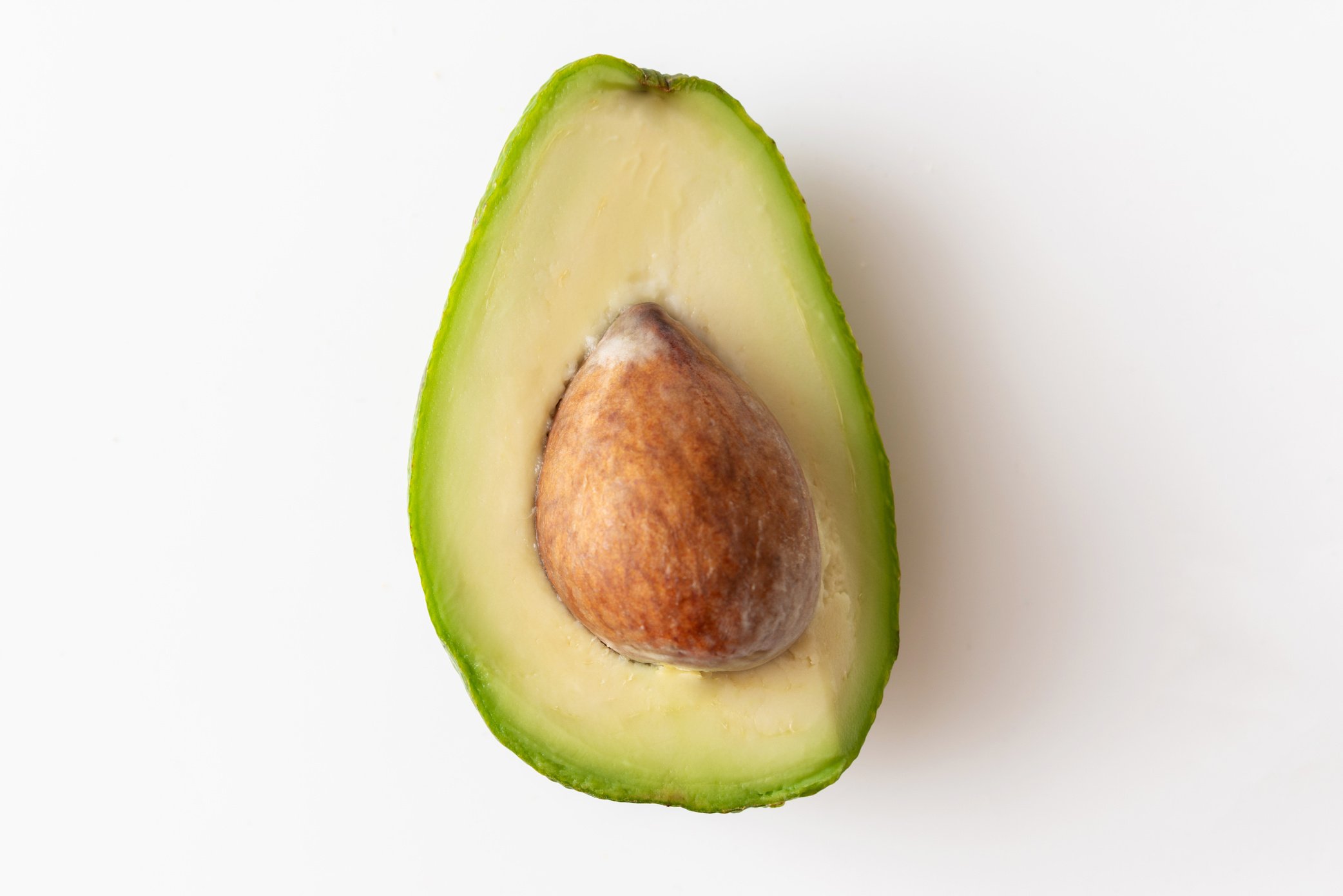 Macro shot of avocedo centered on white background, vegan food with healthy oils and fiber